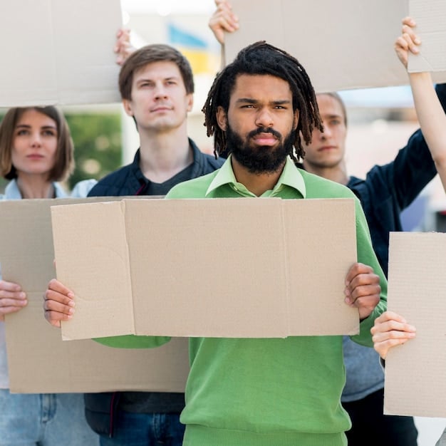A diverse group protesting with signs during a play. The play highlights themes of inequality and social class.