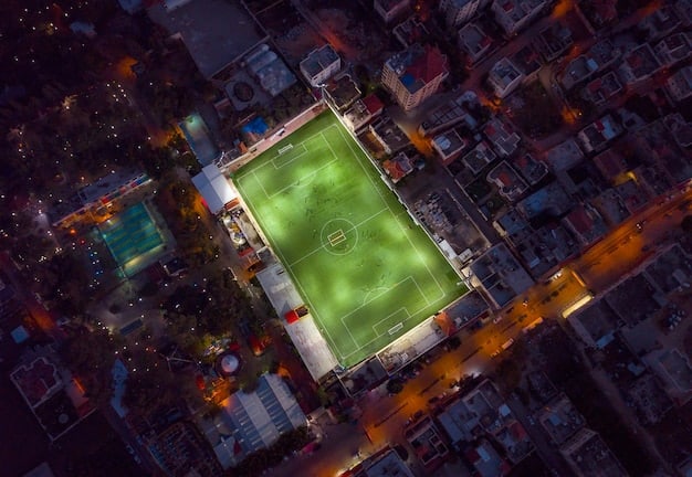 An aerial view of a high school football field at night, with the stadium lights casting a dramatic glow over the scene, symbolizing the intensity and drama that unfolds within Euphoria's setting.